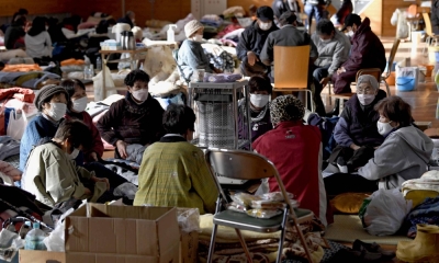 People gather around a heater at an evacuation center in the town of Anamizu, Ishikawa Prefecture, on Monday, following the powerful New Year's Day earthquake that hit the area.