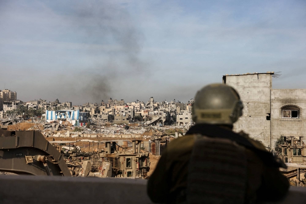 An Israeli soldier looks on as smoke rises from Gaza on Monday.