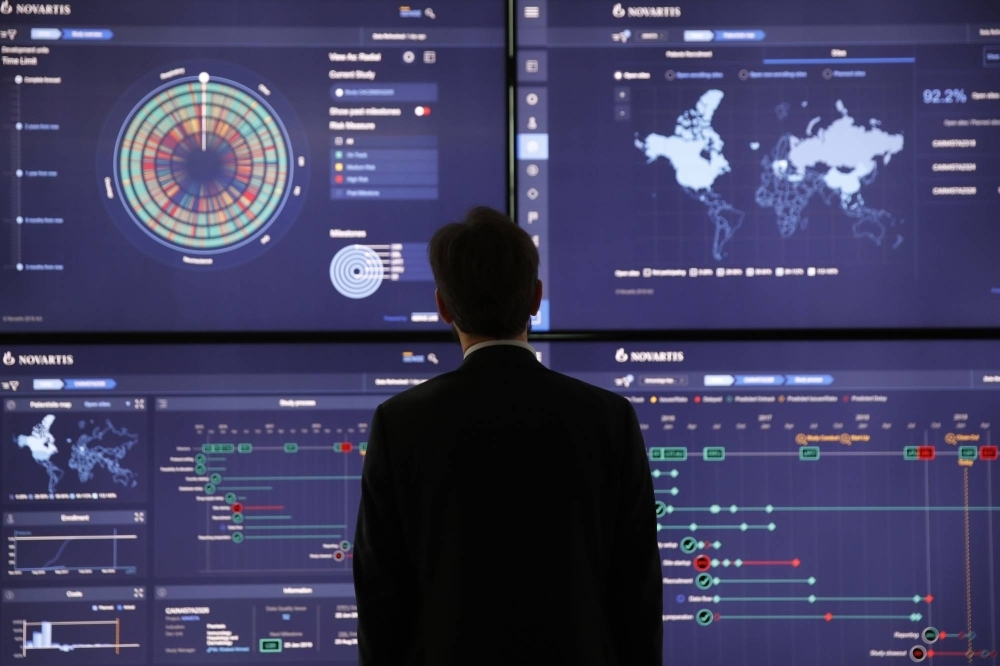 An employee looks at data on screens in the high-tech command center at the Novartis AG campus in Basel, Switzerland.