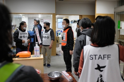 Shu Kokaji (center) speaks with fellow volunteers on Saturday at Sunlife Plaza, an evacuation center in Nanao, Ishikawa Prefecture. At the facility, he aims to bring people joy in some aspects of evacuee life.