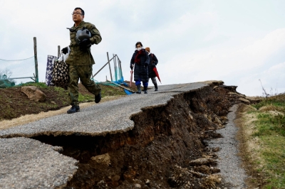 A member of the Self-Defense Forces leads residents from Fukamimachi, a village isolated by the Jan. 1 earthquake, to safety in Wajima, Ishikawa Prefecture on Saturday.