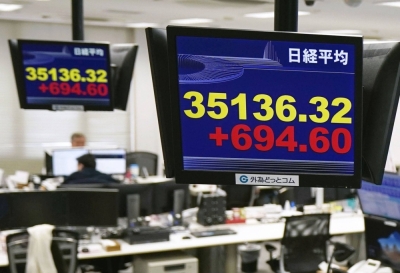 Monitors at a foreign exchange dealer show the Nikkei Stock Average rising above 35,000 during morning trading in Tokyo on Thursday.