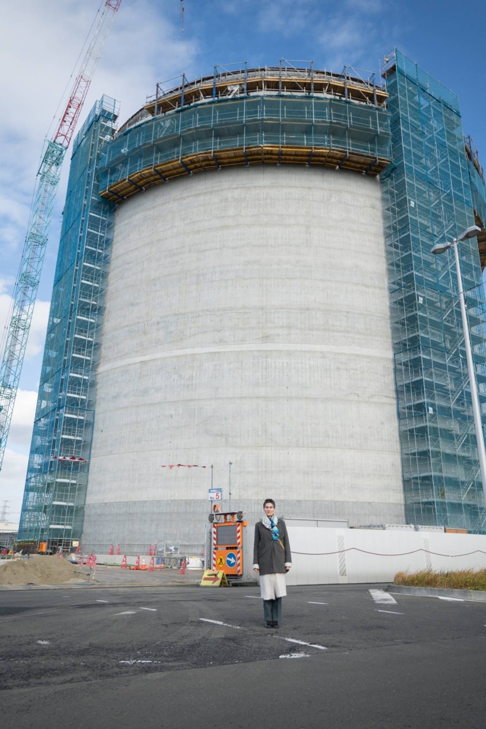 Conservation North’s Michelle Connolly stands in front of an under-construction storage tank at Sumitomo Corp.’s Sendai biomass power plant.