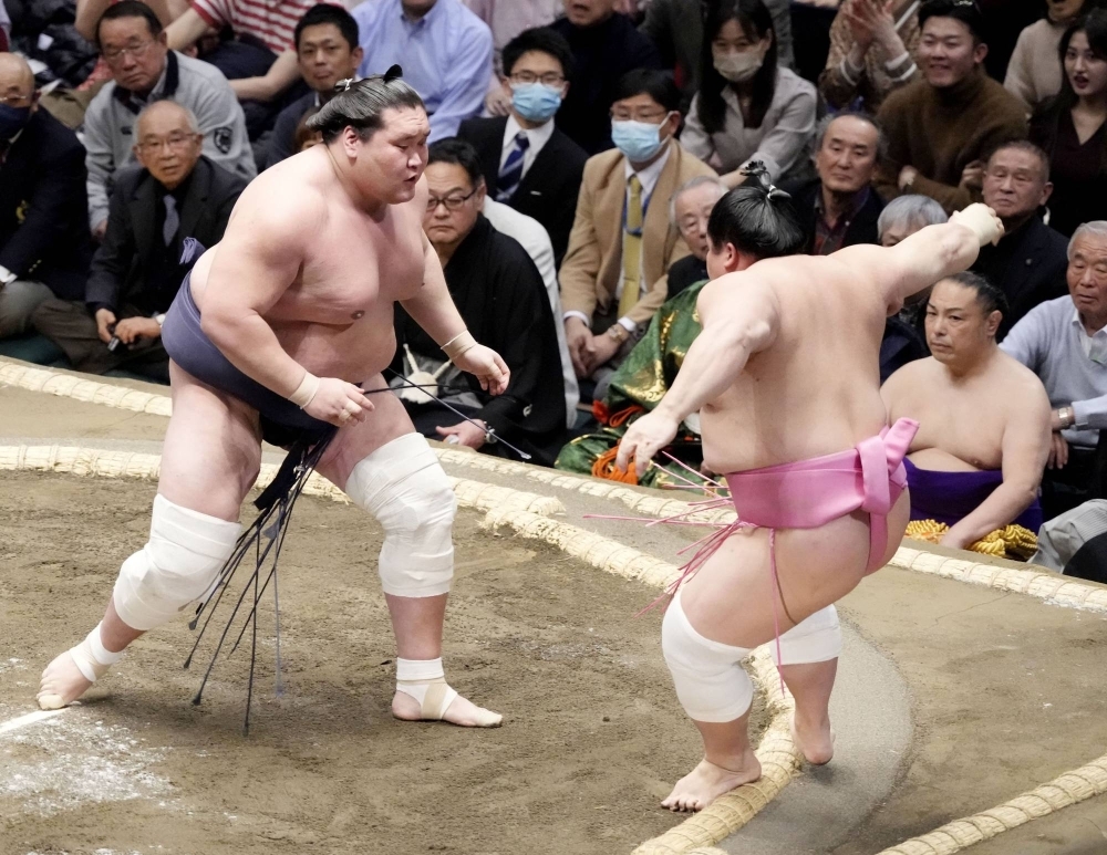 Terunofuji (left) shoves out Ura to win his first bout at the New Year Grand Sumo Tournament on Sunday in Tokyo. 