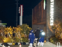 Police officers examine the area around a Starbucks outlet at the Aeon Town Kawanoe shopping facility in Shikokuchuo, Ehime Prefecture, on Sunday night after a shooting incident at the store. | Kyodo