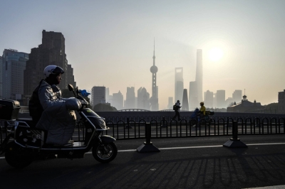 A man rides a scooter over a bridge across from the Lujiazui financial district in Shanghai on Jan. 9.