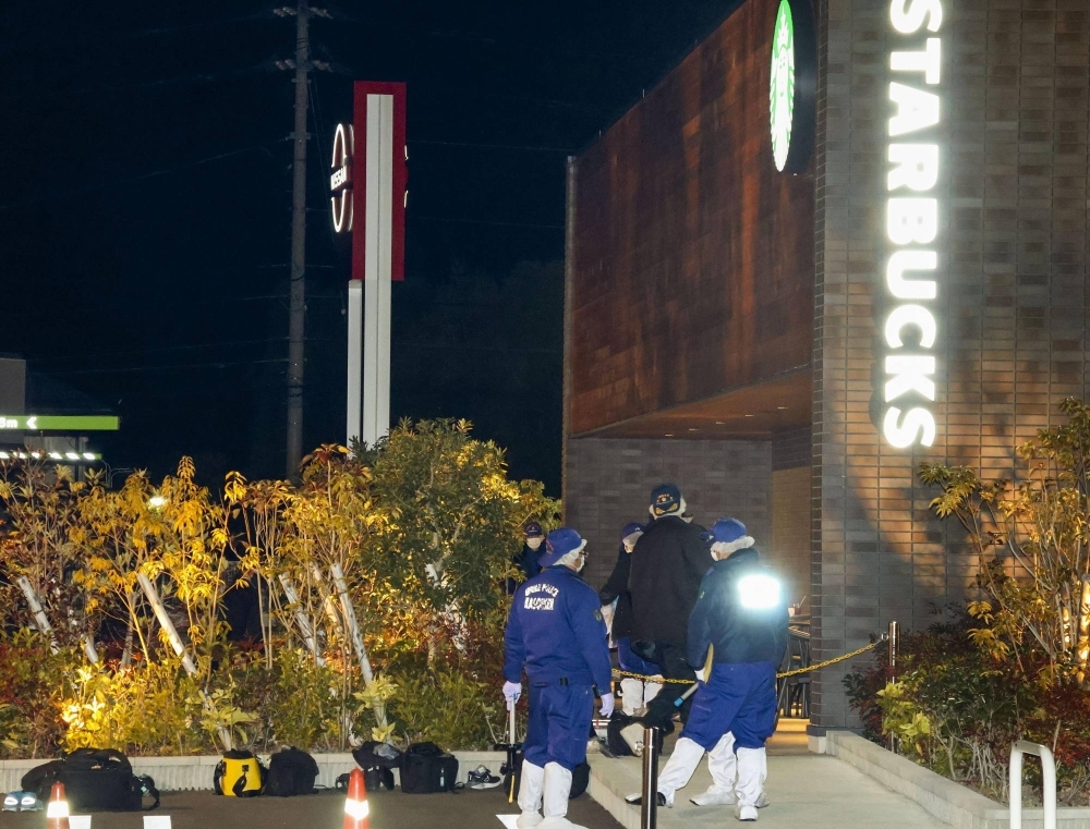 Police officers examine the area around a Starbucks outlet at the Aeon Town Kawanoe shopping facility in the city of Shikokuchuo, in Ehime Prefecture, on Sunday night after a shooting incident at the store.