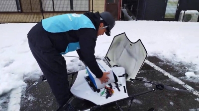 A volunteer places a box containing medicines into a drone on Jan. 8 in the city of Wajima, Ishikawa Prefecture.