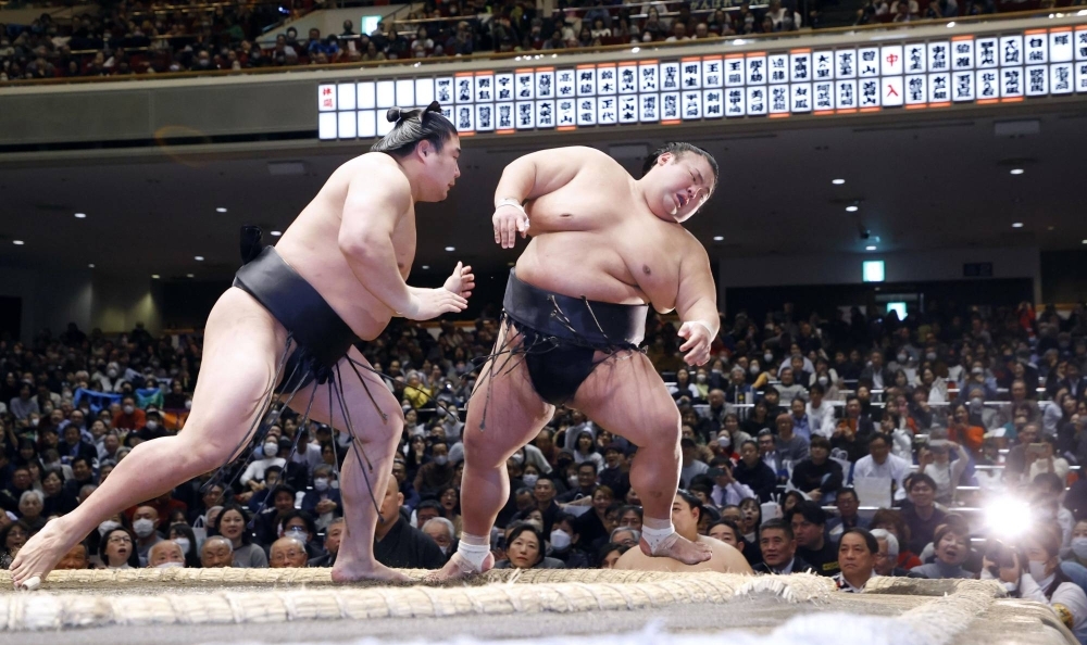 Takakeisho is thrust out of the ring by Wakamotoharu (left) on the third day of the New Year Grand Sumo Tournament.