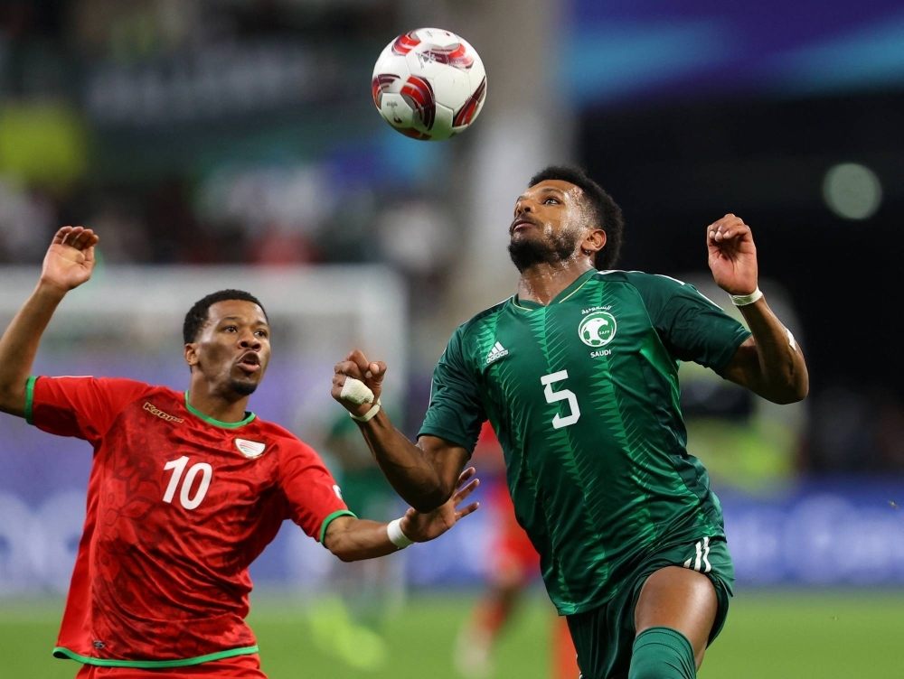 Saudi Arabia's Ali Al-Bulayhi (5) looks to head the ball as he's guarded by Oman's Jameel Al Yahmadi on Tuesday at Khalifa International Stadium in Qatar during round robin play at the Asian Cup. 