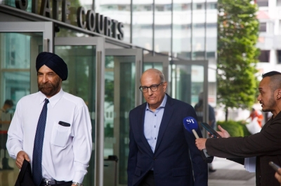 Singapore's former Transport Minister Subramaniam Iswaran (center) and his defense counsel Davinder Singh (left) leave the Singapore State Courts on Thursday.