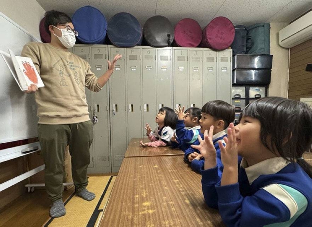 Daisuke Hironaka, deputy head of Ikuno Komorebi Hoikuen, teaches Japanese to children at the day care in Osaka's Ikuno Ward.