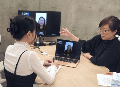 Jiho Yoshimizu (right), representative of a support group for Vietnamese trainees in Japan, listens to a Vietnamese trainee seen in the monitors speaking online in October about her experience of having been instructed by an intermediary organization to undergo contraceptive treatment.