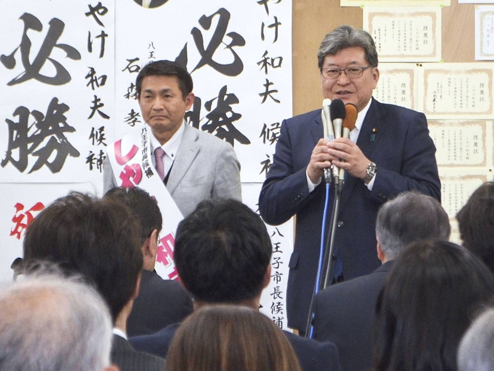 Former LDP Policy Research Council head Koichi Hagiuda (right) speaks in Hachioji, Tokyo, late Sunday night after Kazuo Shiyake won the city's mayoral election.