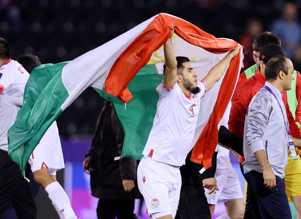 Tajikistan's Rustam Soirov celebrates with a banner after his team defeated Lebanon in an Asian Cup Group A match in Al Rayyan, Qatar, on Monday.