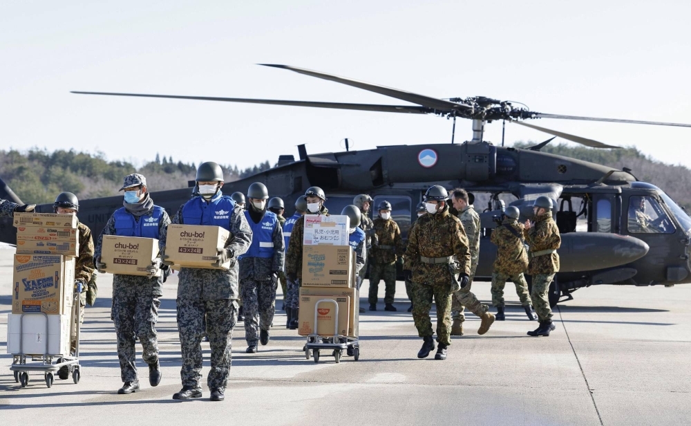 Members of the Self-Defense Forces carry relief goods from a U.S. military helicopter at Noto Airport in Ishikawa Prefecture last week. The airport will resume services for commercial flights on Saturday.