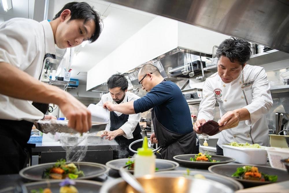 Toshiya Ikehata (second from right) and Meiju Hirata (second from left) at work during an event. The two chefs often worked together at such annual events in the years before the earthquake. 