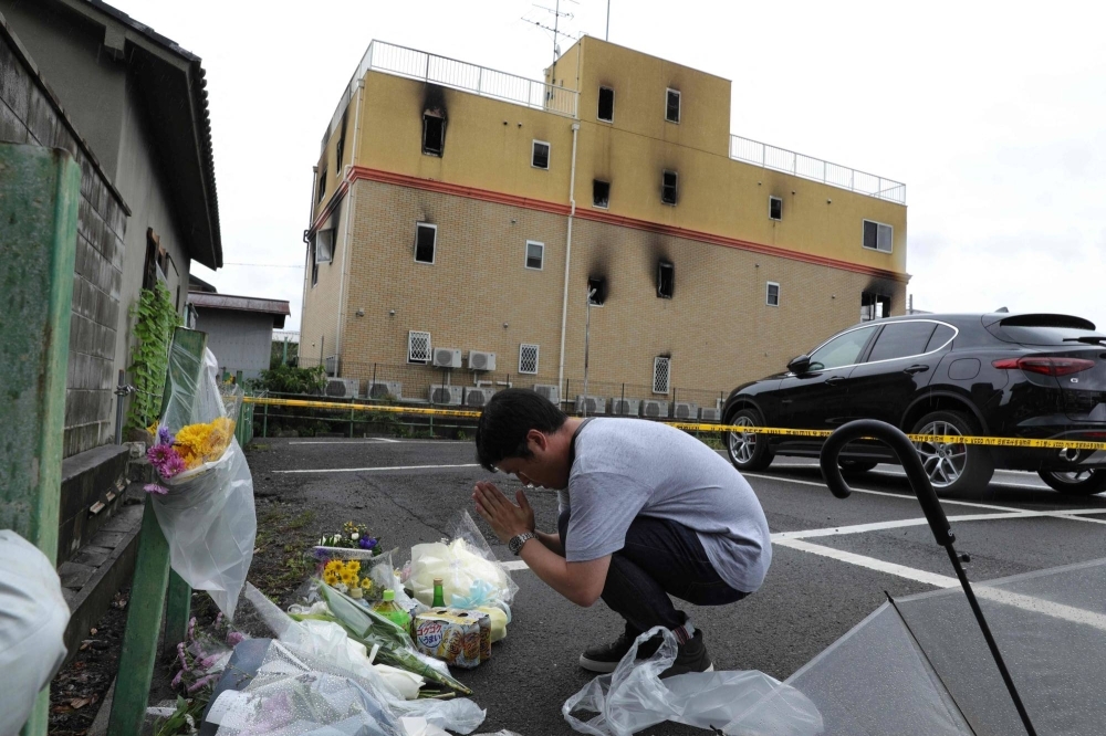A man prays on July 19, 2019, outside the Kyoto Animation building where 36 people died in a fire caused by Shinji Aoba the previous day.