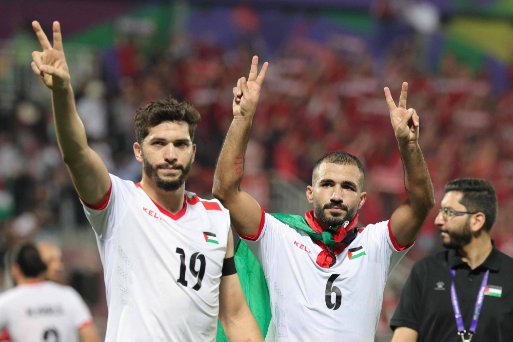Palestine forward Mahmoud Wadi (19) and midfielder Oday Kharoub (6) greet supporters after the team's win over Hong Kong at Abdullah bin Khalifa Stadium in Doha on Tuesday. 