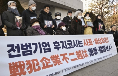 Plaintiffs hold up a banner outside South Korea's Supreme Court in Seoul on Thursday ahead of a wartime labor ruling by the top court.