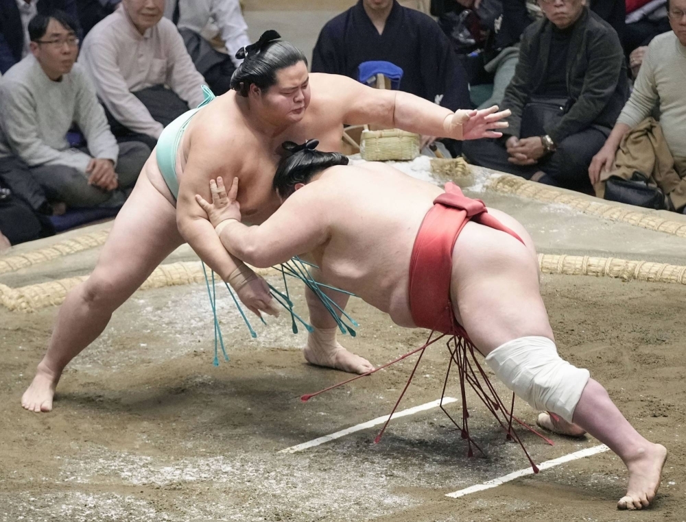 Kotonowaka (left) defeats Onosho at the New Year Grand Sumo Tournament on Thursday.