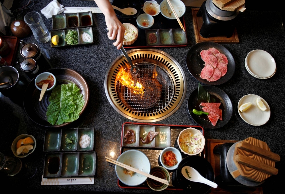 A woman grills a piece of beef at a barbeque restaurant in Yokohama. Greenhouse gas emissions from food amount to a third of all human-caused emissions.