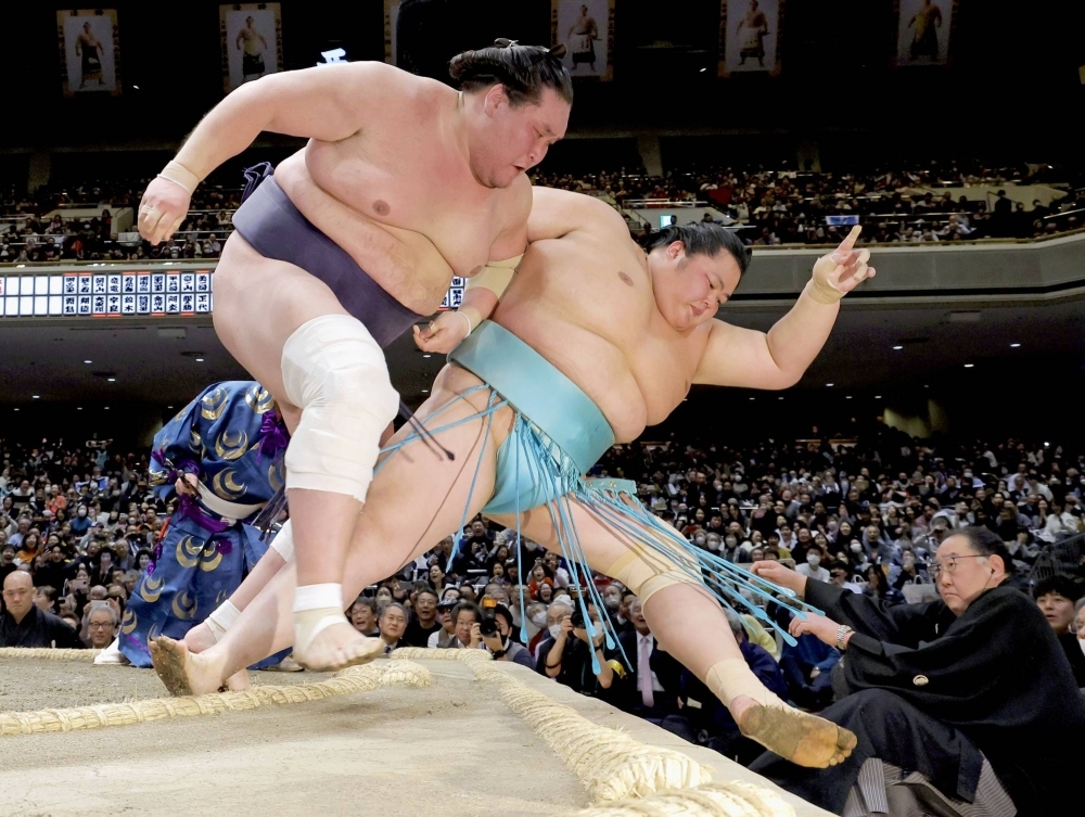 Terunofuji (left) clinches the title by shoving out Kotonowaka in a tie-breaker on Sunday at Ryogoku Kokugikan in Tokyo.