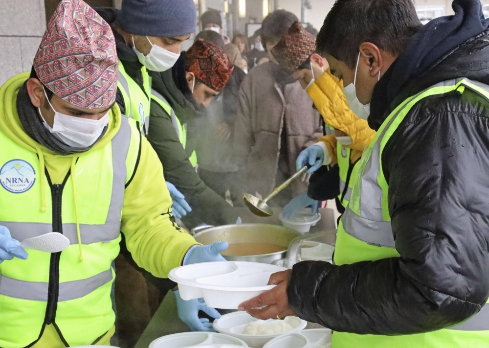 A team of volunteers from the Non-Resident Nepali Association in Japan serves curry to evacuees in Suzu, Ishikawa Prefecture, on Jan. 13.
