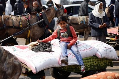 A Palestinian girl sits on bags of flour distributed by the United Nations Relief and Works Agency in Rafah in the southern Gaza Strip on Monday.