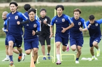 Japan's Takumi Minamino (front left) trains alongside his teammates in Doha on Monday. | Kyodo