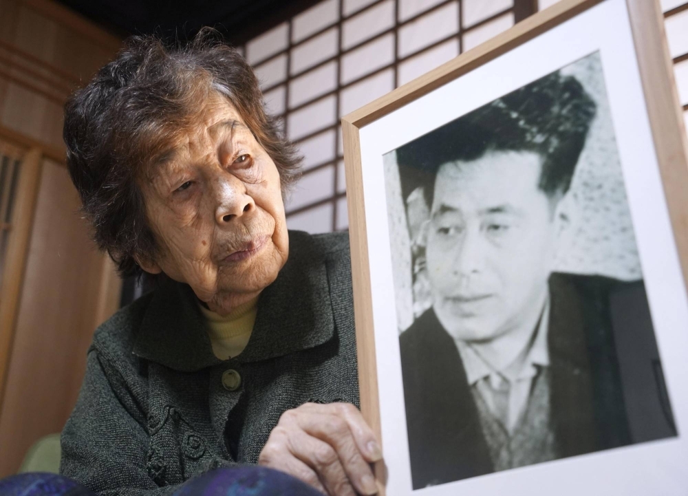 Miyoko Oka holds a photo of her brother, Masaru Okunishi, in Yamazoe Village, Nara Prefecture, in November 2023.