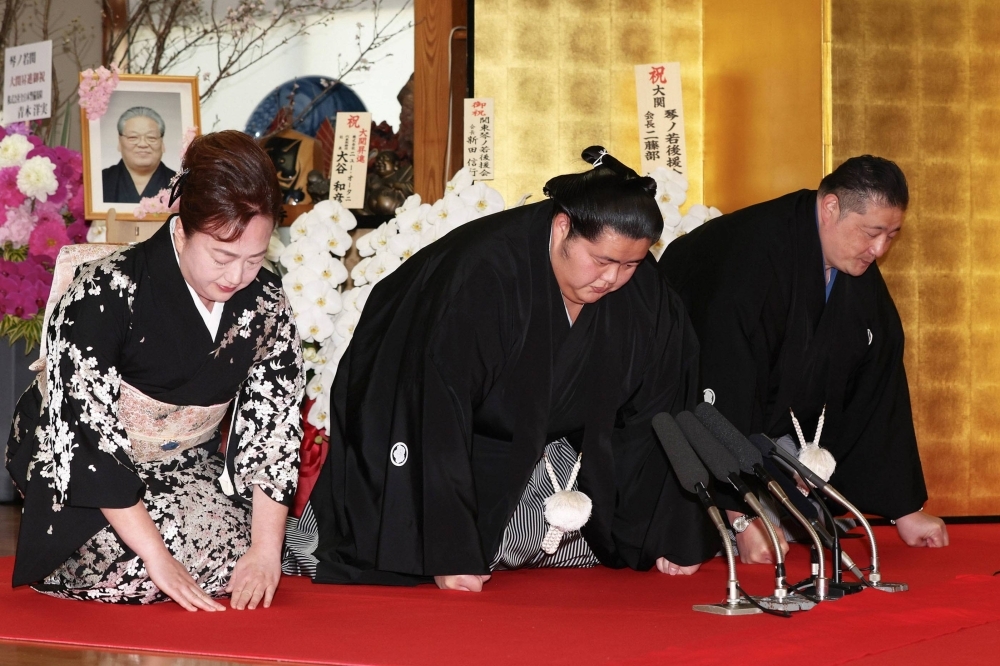 Sumo wrestler Kotonowaka (center) accepts his promotion to the sport's second-highest rank of ozeki during a ceremony at the Sadogatake stable in Matsudo, Chiba Prefecture, on Wednesday. Sitting next to him is his father and stablemaster, Sadogatake.