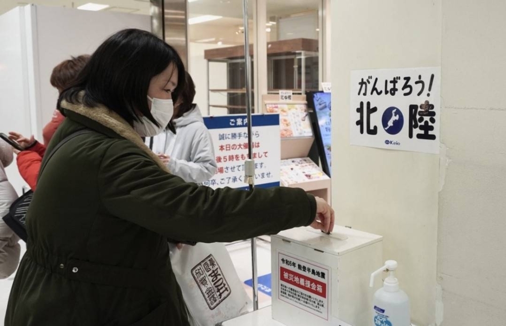 A woman makes a donation for people affected by the Noto Peninsula earthquake set up at Shinjuku's Keio Department Store's in Tokyo on Monday.