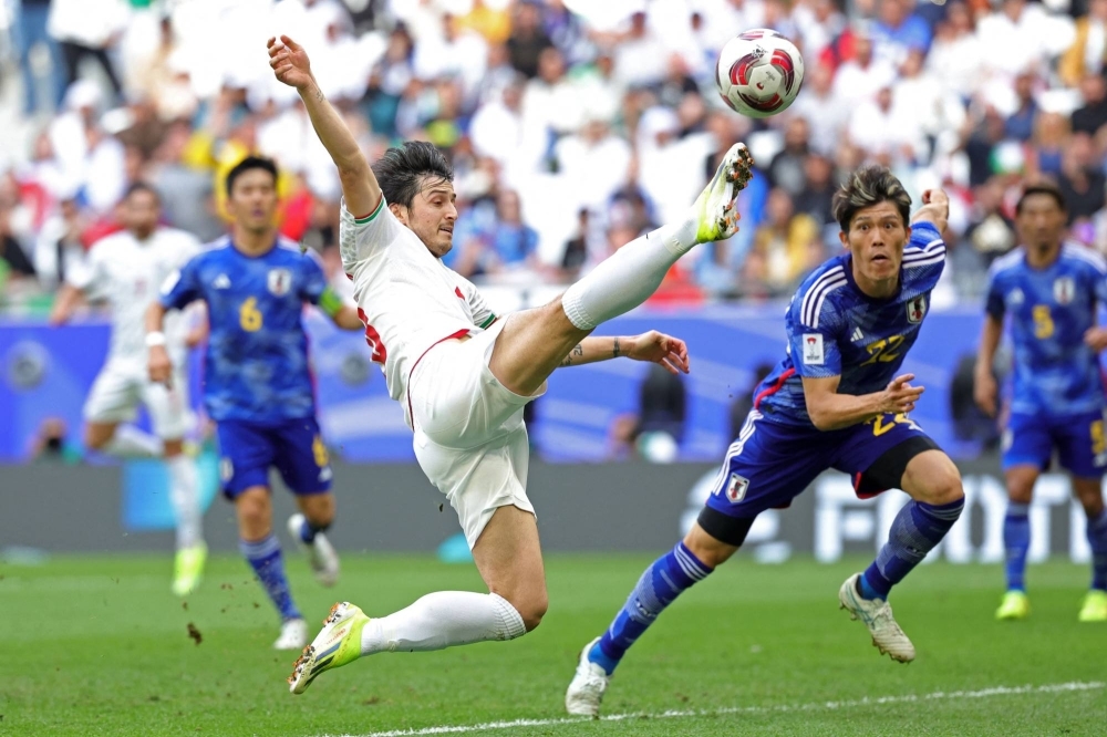 Iran forward Sardar Azmoun shoots the ball past Japan defender Takehiro Tomiyasu during the teams' quarterfinal clash at the Asian Cup in Qatar on Saturday. 