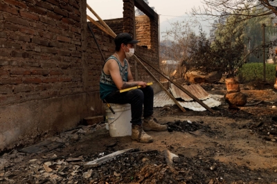 A man sits near the remains of burnt houses following the spread of wildfires in Vina del Mar, Chile, on Saturday. 
