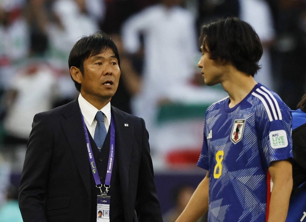 Japan coach Hajime Moriyasu and Takumi Minamino look dejected after the team lost its quarterfinal match to Iran on Saturday. 