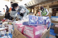 People sort relief supplies, including sanitary napkins, diapers and baby formula, in Suzu, Ishikawa Prefecture, on Sunday, over a month after a New Year's Day quake hit the area. | Kyodo