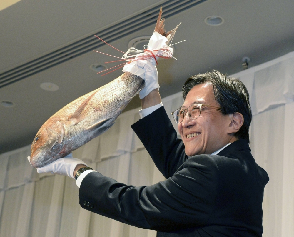 Newly elected Kyoto Mayor Koji Matsui receives a sea bream as a congratulatory gift in Kyoto on Sunday.