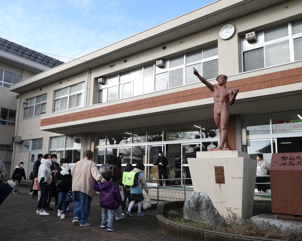 Elementary school students arrive at Wajima Senior High School in Ishikawa Prefecture as classes resume at vacant classrooms at the school on Tuesday.