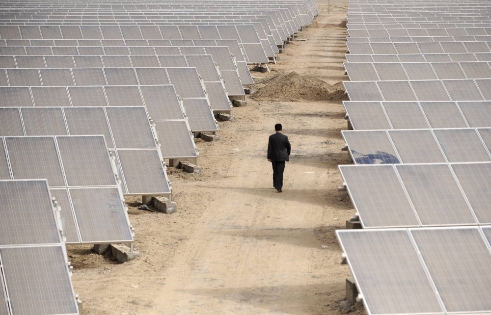 A man walks through panels at a solar power plant under construction in Aksu, in the Xinjiang Uyghur Autonomous Region of China, in 2012.