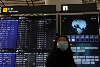 A traveler walks past a flight information display at the Beijing Capital International Airport on Feb. 2 ahead of the Lunar New Year holiday that begins on Saturday in China. | REUTERS