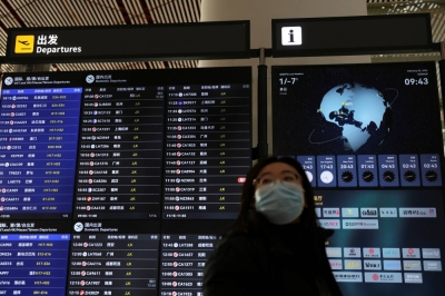 A traveler walks past a flight information display at the Beijing Capital International Airport on Feb. 2 ahead of the Lunar New Year holiday that begins on Saturday in China.