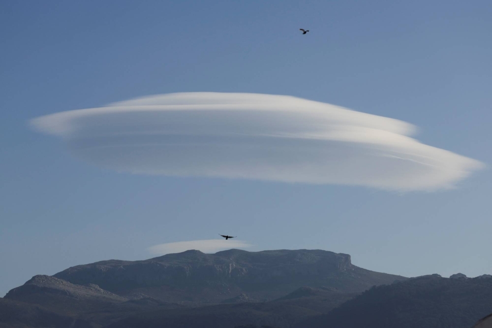 A lenticular cloud is seen over a mountain at sunset in a clear sky, due to an anticyclone during a prolonged drought with warming temperatures and lack of rain in winter, in Ronda, Spain, on Tuesday.