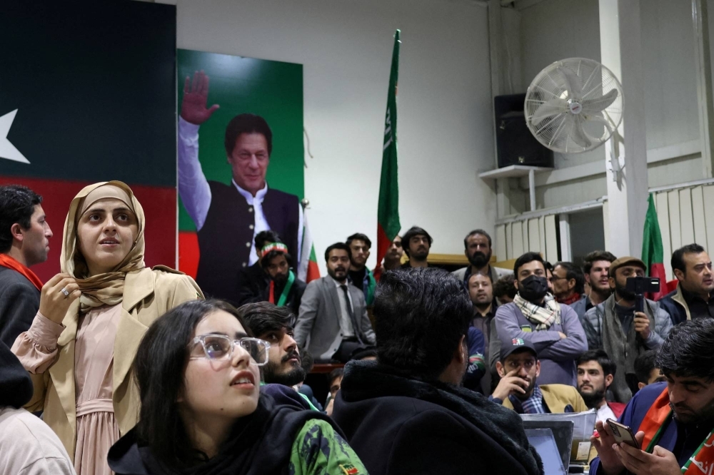 Volunteers for former Prime Minister Imran Khan's party Pakistan Tehreek-e-Insaf watch election results on TV in Islamabad on Thursday. 