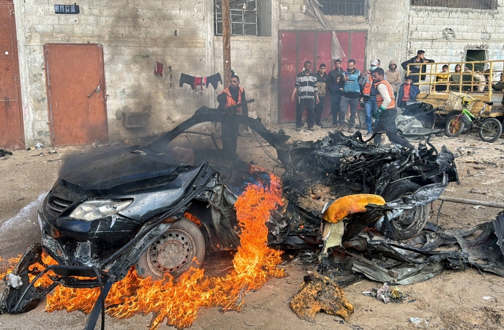 A firefighter extinguishes a burning car hit by an Israeli strike in Rafah on Saturday. 