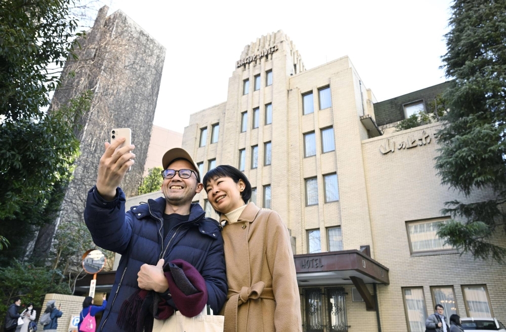 A couple takes a commemorative photo in front of Hilltop Hotel in Tokyo on Monday, the final day before its closure for an undetermined period. 