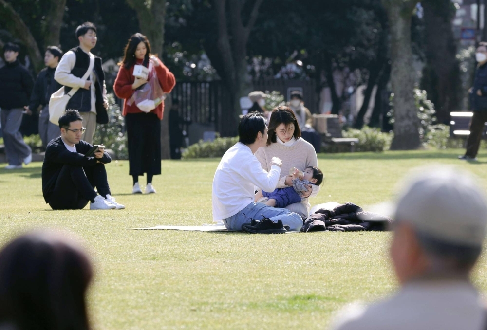 People relax at a park in the city of Fukuoka on Tuesday as high temperatures were recorded across the country.