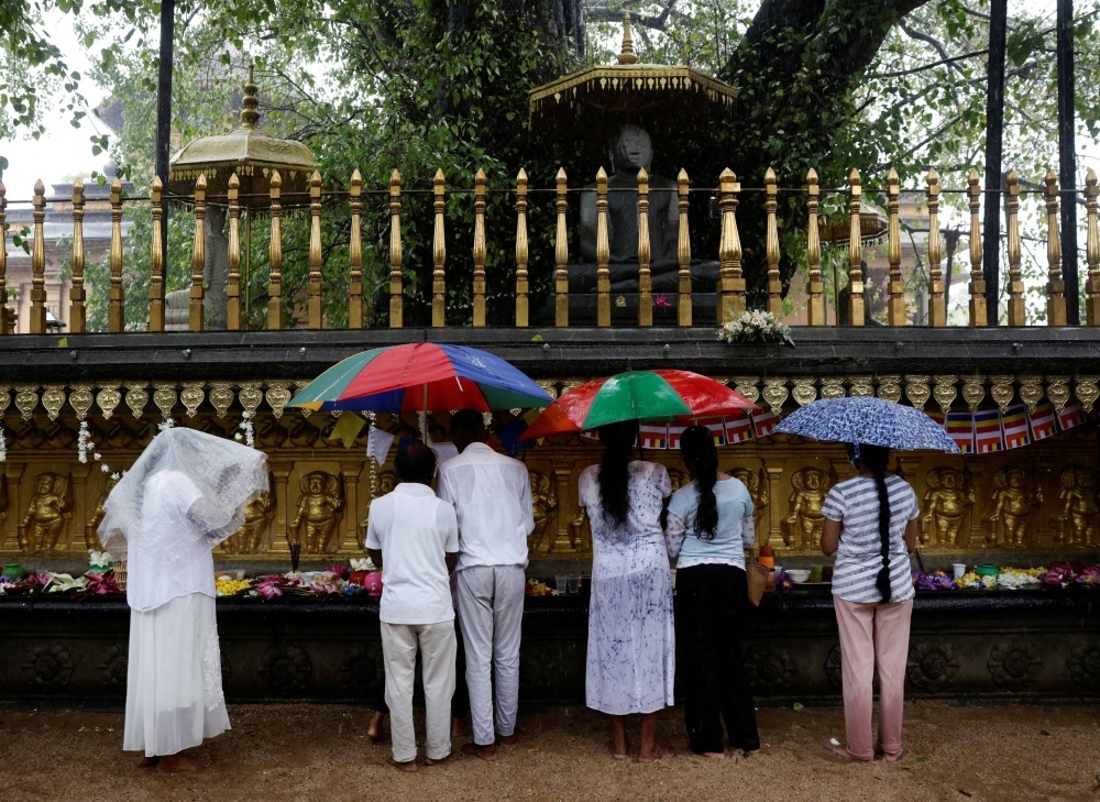 Buddhist devotees worship in heavy rain in Colombo, Sri Lanka, on May 5, 2023. 