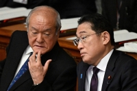 Finance Minister Shunichi Suzuki (left) speaks with Prime Minister Fumio Kishida during a plenary session of the Lower House in Tokyo on Jan. 30. | AFP-JIJI
