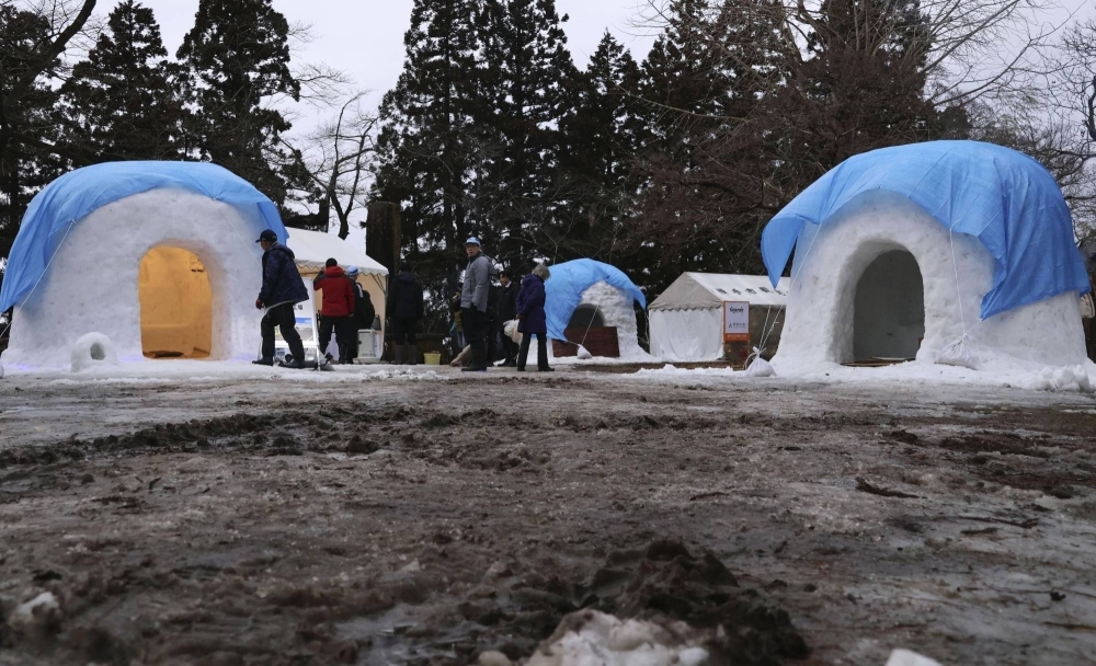 Blue sheets cover snow huts to protect them from the rain during an annual festival in Yokote, Akita Prefecture, on Thursday.